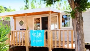 A wooden cabin with a deck, a circular window, and a sign that reads 'j'ai piscine'. - Family Lodge Near Beach & Pool (Hyères)