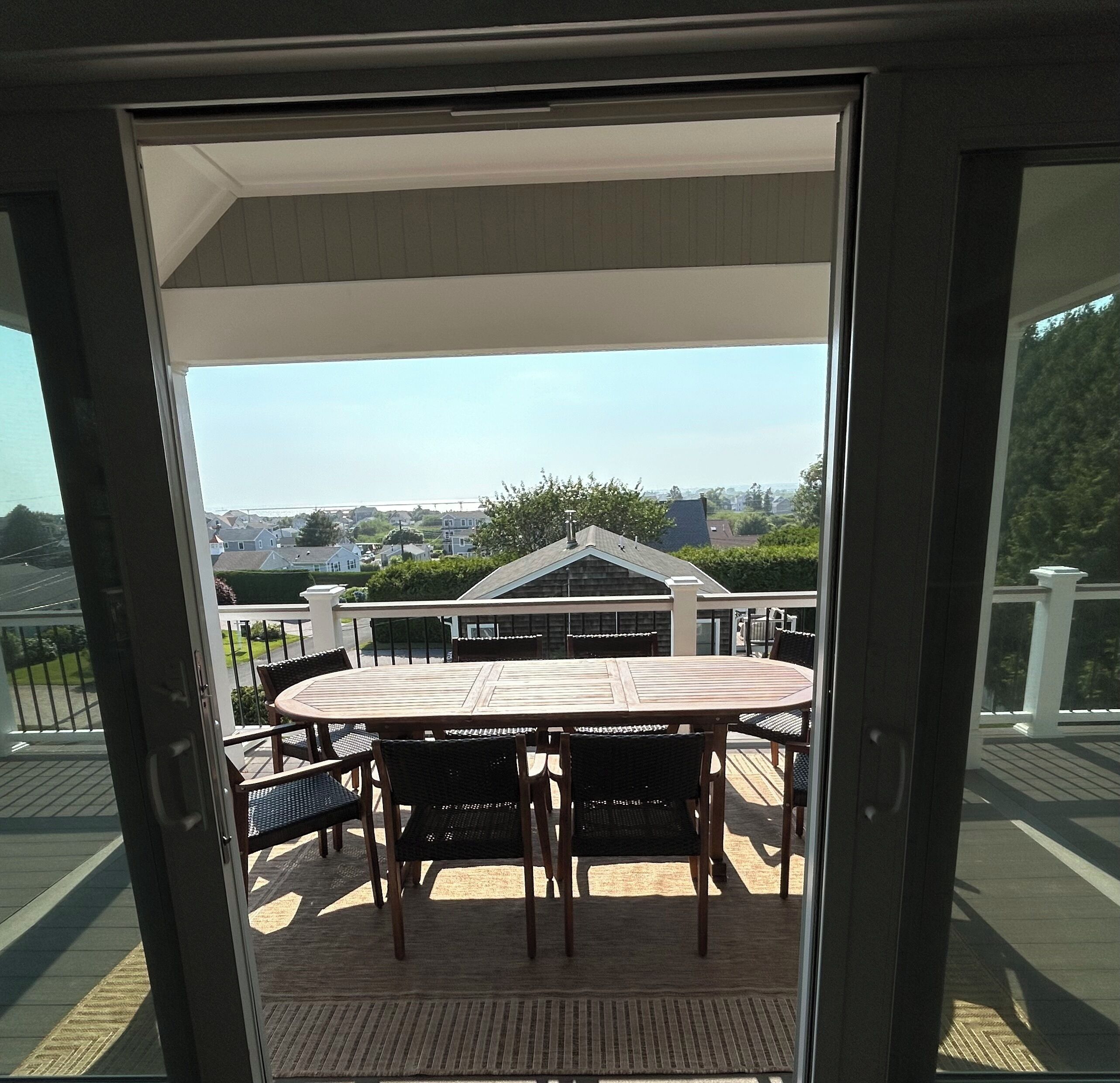 Un balcone con tavolo e sedie, vista su case e cielo sereno.