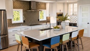 A modern kitchen with a central island, stainless steel appliances, and a herringbone-patterned backsplash. - Amazing Narragansett house - 5+ bdrm - Brand New!! (Narragansett)