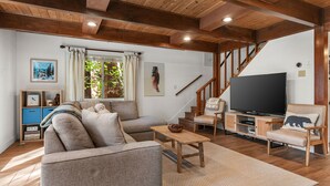 Ein Wohnzimmer mit einer Couch, einem Couchtisch, einem Fernseher und einer Holztreppe.