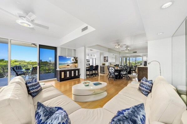 A modern living room with a sofa, coffee table, and dining area. - Ocean Views. C202 Vista Waikoloa (Waikoloa Beach Resort)