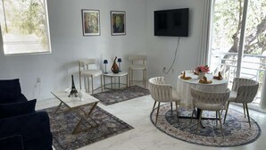 A living room with a sofa, a coffee table, a TV, and a balcony with a railing. - Bed & Breakfast Coconut Grove Miami (Miami)