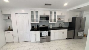 A modern kitchen with white cabinetry, stainless steel appliances, and a tiled floor. - Bed & Breakfast Coconut Grove Miami (Miami)