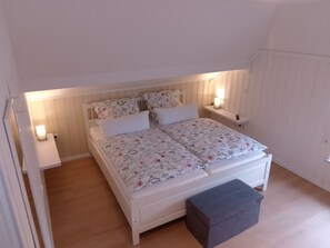 Une chambre à coucher avec un lit double, deux tables de chevet, une commode et un banc.