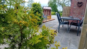 Eine Terrasse mit Ziegelmauer, herzförmiger Dekoration und Gartenmöbeln.