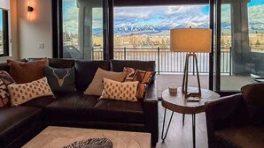 Ett modernt vardagsrum med ett stort fönster, en soffa, ett soffbord och en lampa.