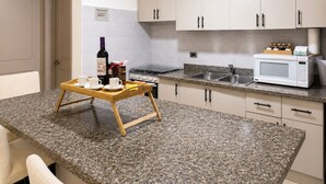 Une cuisine dotée de plans de travail en granit, d’une cuisinière à gaz, d’un four à micro-ondes et d’un ventilateur de plafond.