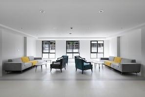 Ein modernes Interieur mit zwei grauen Sofas, Türkis-farbenen Ohrensesseln und kleinen Tischen.
