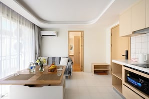 Eine moderne Küche mit Einbauofen, ein Essbereich mit Tisch und Stühlen sowie ein Wohnbereich mit Sofa und Fernseher.