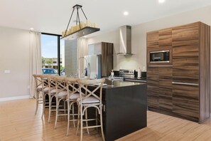 Una cocina moderna con una isla central, armarios de madera y un comedor con sillas.