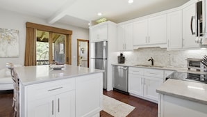 Una cocina moderna con armarios blancos, electrodomésticos de acero inoxidable y una isla grande.