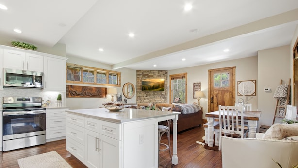 Una cocina amplia con armarios blancos, una isla grande y un comedor con mesa y sillas de madera.