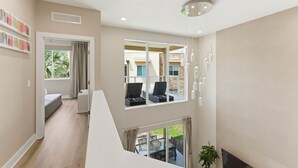 A modern interior with a staircase, a balcony with outdoor seating, and a large window offering a view of the outside. - Designer 4BR Getaway, Sleek Laminate Floors (Four Corners)