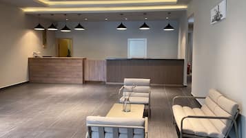 A reception area with a wooden reception desk, a waiting area with chairs and a sofa, and a fire extinguisher on the wall.