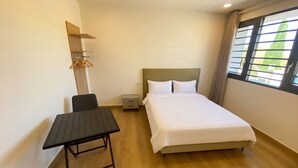 A hotel room with a bed, a desk, a chair, a nightstand, and a window with curtains.
