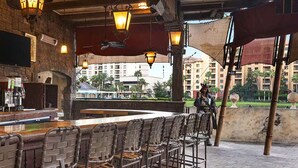 A bar area with a stone wall, bar stools, and a variety of liquor bottles. - 2-bedroom deluxe, full kitchen, resort Lake Buena Vista, Disney World - sleeps 6 (Lake Buena Vista)