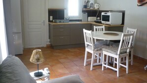 Une cuisine compacte avec un coin repas, un four à micro-ondes, une bouilloire et une horloge murale.