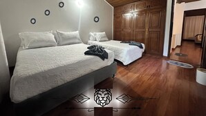 Quarto com duas camas, teto de madeira e um guarda-roupa.
