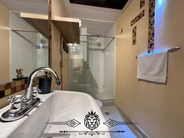 Un baño moderno con un lavamanos grande, una cabina de ducha de vidrio y un perchero para toallas.
