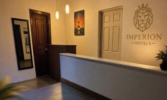 Zona de recepción de hotel con mostrador, una puerta, un cartel en la pared y un cuadro enmarcado.