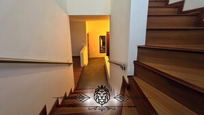 Uma escadaria com degraus e guarda-corpos de madeira, conduzindo a um espaço interior.