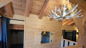 Un interior de madera con techo inclinado, una escalera y un candelabro original.