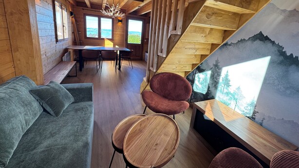 Un interior de madera con un sofá, sillas, una mesa de comedor y una escalera con un mural.