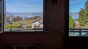Una habitación con techo de madera, un candelabro, una mesa y dos ventanas que dan a vistas de la ciudad y zonas verdes.