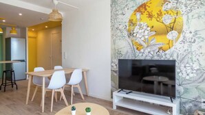 A modern living room with a dining area, a flat-screen TV on a stand, and a floral wallpaper. - Private Room in a Shared Apartment - Bron (Bron)