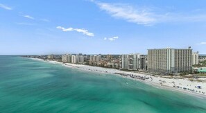 Paisagem costeira urbana com arranha-céus, uma praia e céu claro.