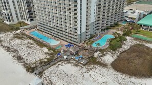 Ein Hochhaus-Hotel mit mehreren Schwimmbecken, einem Strandbereich und einer Promenade.