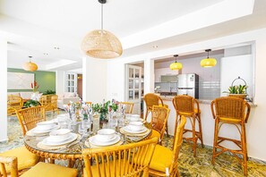 A dining area with round tables, yellow wicker chairs, and hanging pendant lights.