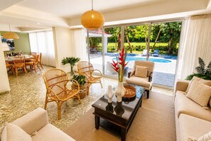 A spacious living area with a pool view, wicker furniture, and a modern coffee table.
