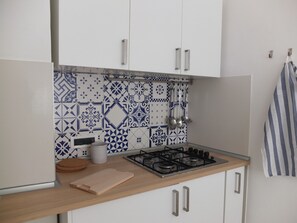 A kitchen with white cabinets, a patterned backsplash, a gas stove, and a wooden countertop. - Santangiolese House - In the heart of Sant'Angelo (Sant'Angelo)