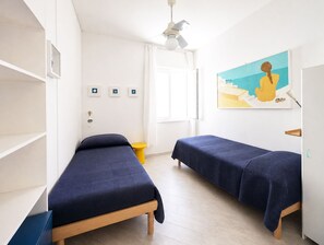A room with two beds, a window, a ceiling fan, and a painting on the wall. - Santangiolese House - In the heart of Sant'Angelo (Sant'Angelo)