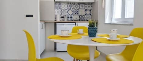 A modern kitchen with white cabinets, a blue and white tile backsplash, and a window with natural light.