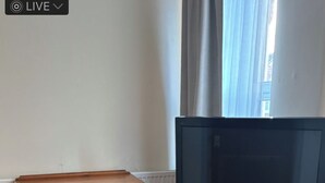 A wooden dresser, a television on a stand, and a radiator in a room with wooden flooring. - Eden homez (Bristol)