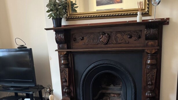 A room with a fireplace, a bed with a yellow bedspread, a television, and a mirror. - Eden homez (Bristol)