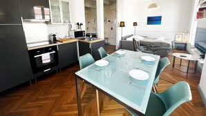 A modern kitchen with a dining area, a bed, and a TV. - Balcon Palais Excelsior Grimaldi (Nice)