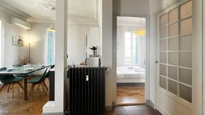 A hotel room with a dining area, a radiator, a bed, and a door with frosted glass panels. - Balcon Palais Excelsior Grimaldi (Nice)