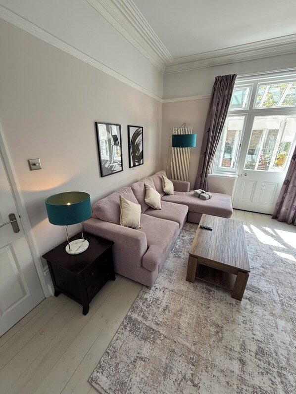 A living room with a sofa set, a coffee table, a floor lamp, and a radiator.