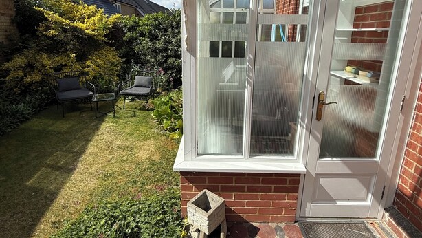 A conservatory with a glass roof, a brick exterior, and a tiled patio. - Red House  (Guildford)