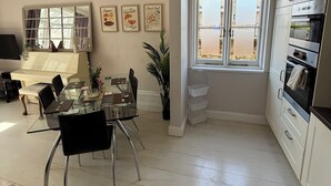 A modern kitchen with white cabinets, a built-in oven, and a window with blinds. - Red House  (Guildford)