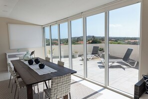 Ein geräumiger Balkon mit Essbereich, großen Schiebeglastüren und Blick auf die umliegende Landschaft.