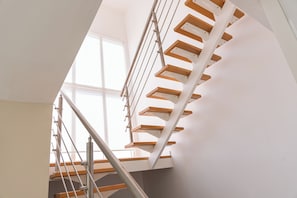 Eine moderne Treppe mit Holzstufen und Metallgeländern, die zu einer oberen Etage führt.
