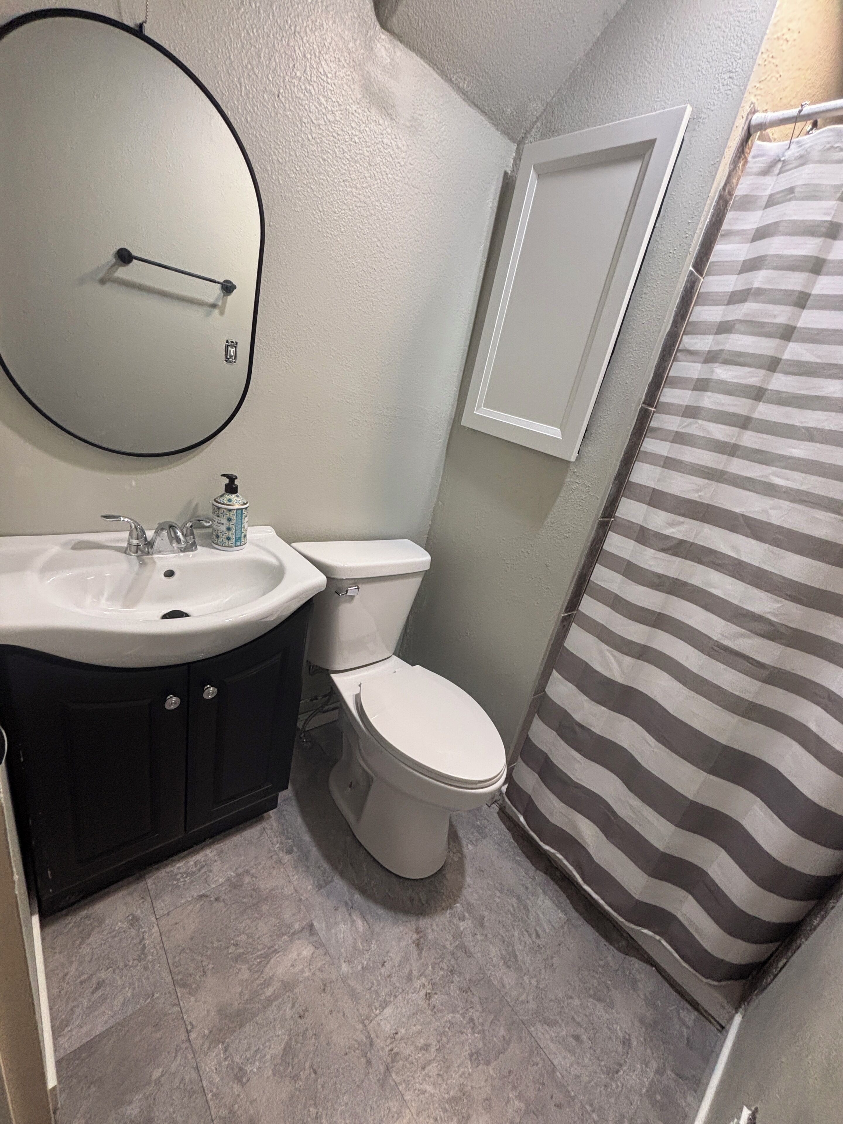 Un baño con lavamanos, inodoro y espejo.