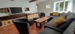Ein Wohnzimmer mit einer Couch, Sesseln, einem Fernseher und einer Steinwand.