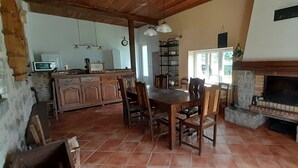 Una cocina rústica con armarios de madera, una mesa de comedor con sillas, una chimenea y un piso de baldosas.