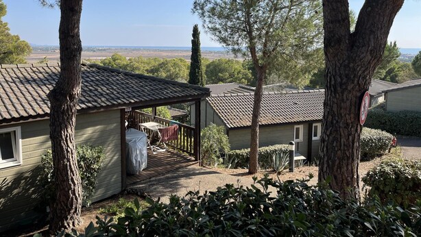A residential property with a covered patio, a view of the landscape, and a clear sky.