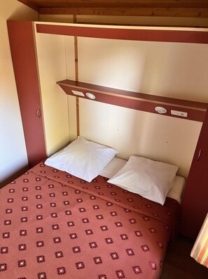 A single bed with two pillows and a patterned bedspread in a room with wooden walls and a slanted ceiling. - Mediterranean Family Cottage Retreat (Agde)